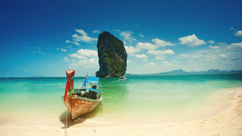 סירה על חוף ים כחול ירוק בתאילנד.