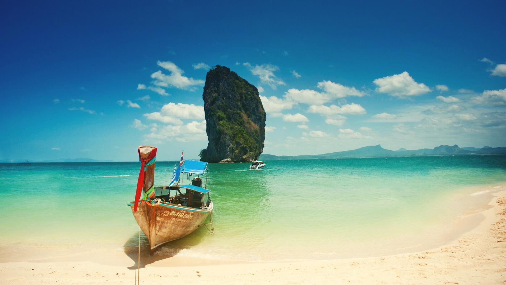 סירה על חוף ים כחול ירוק בתאילנד.