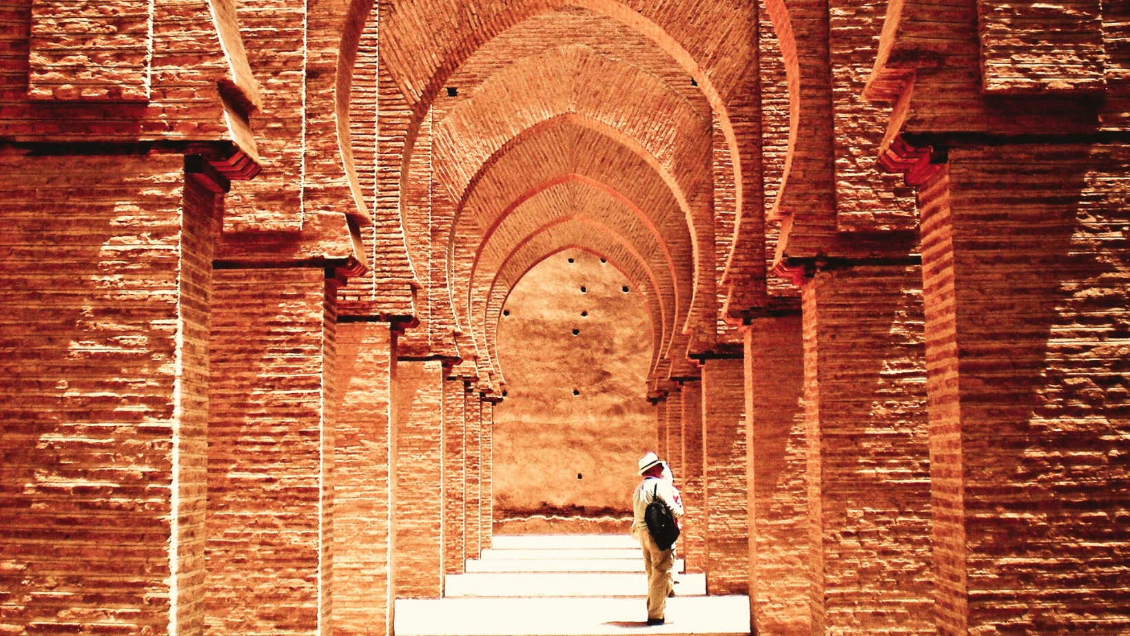 קשתות במסגד במרוקו עם תייר שעומד במרכז.מרוקו