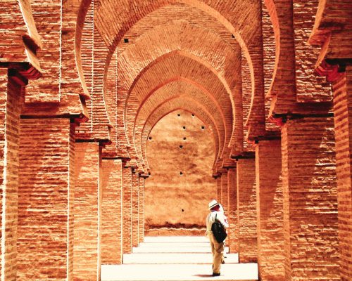 קשתות במסגד במרוקו עם תייר שעומד במרכז.מרוקו